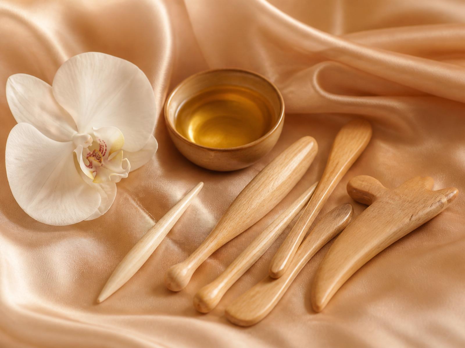 Wood therapy tools resting on champagne silk in the It Girl Sculpt atelier
